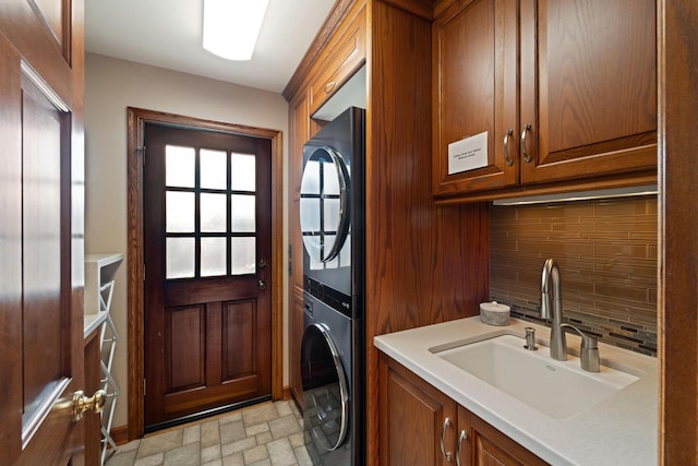 clothes washing area featuring stacked washer / dryer, cabinet space, and a sink