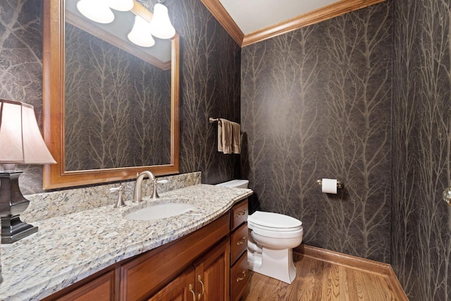 half bathroom featuring vanity, crown molding, toilet, and wood finished floors