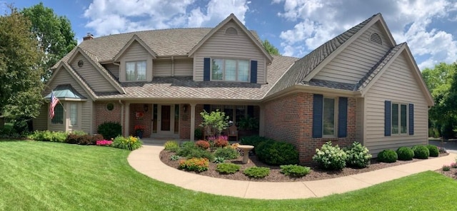 view of front of home featuring a front lawn, covered porch, and brick siding