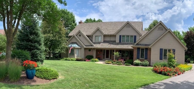 view of front of house with brick siding, a chimney, and a front yard