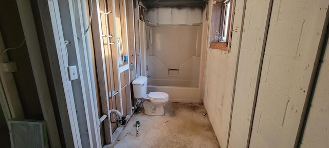 bathroom with concrete block wall, toilet, and bathing tub / shower combination