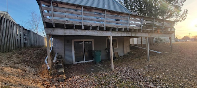 back of house at dusk with concrete block siding and fence