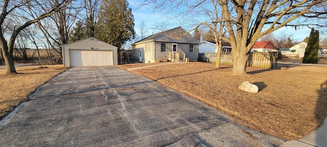 single story home featuring entry steps, aphalt driveway, fence, an outdoor structure, and a garage