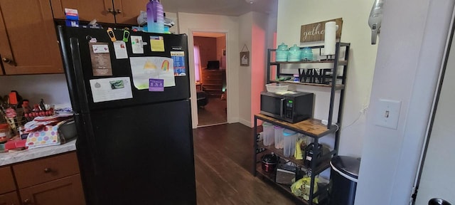 kitchen featuring dark wood finished floors, black appliances, light countertops, and baseboards