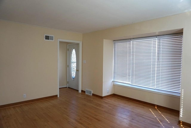 unfurnished room with visible vents, baseboards, and wood finished floors