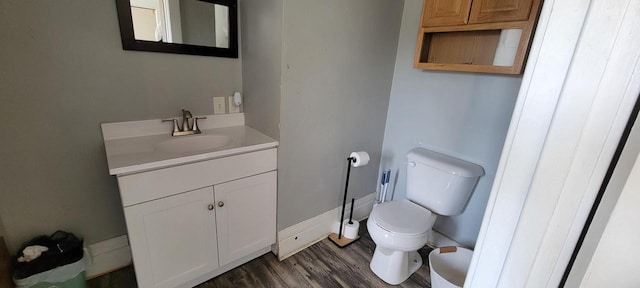 bathroom with baseboards, toilet, wood finished floors, and vanity