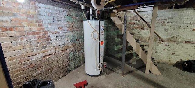 unfinished basement featuring gas water heater and brick wall