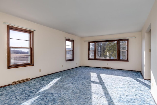 spare room with carpet flooring, baseboards, and visible vents