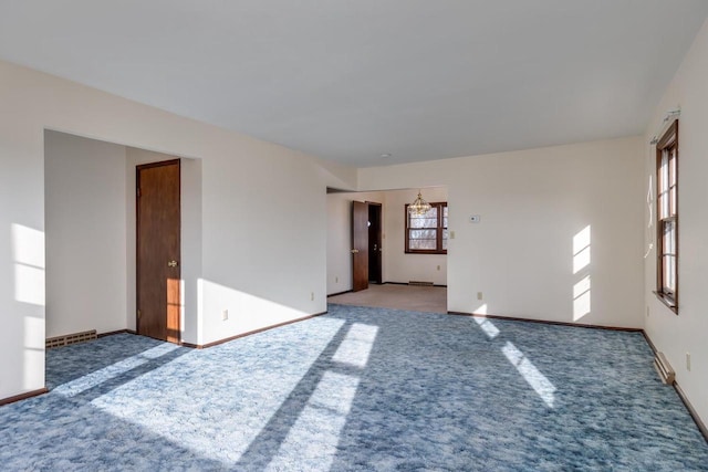 spare room featuring a notable chandelier, carpet, and baseboards