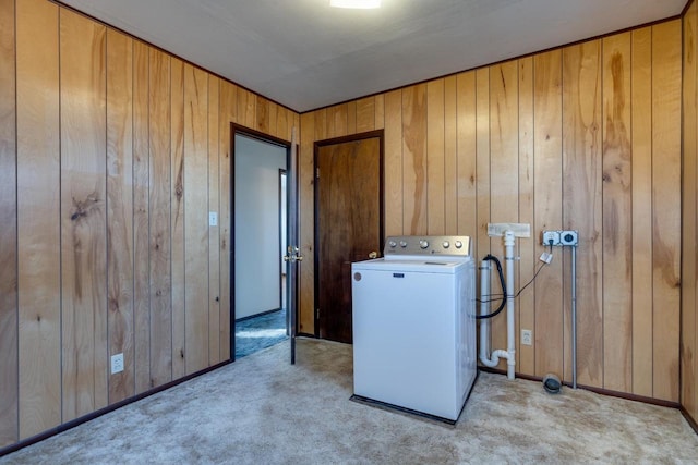 clothes washing area featuring light carpet, wooden walls, washer / dryer, and laundry area