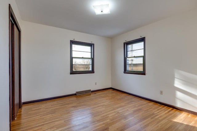 unfurnished room with a wealth of natural light, visible vents, and light wood-style flooring