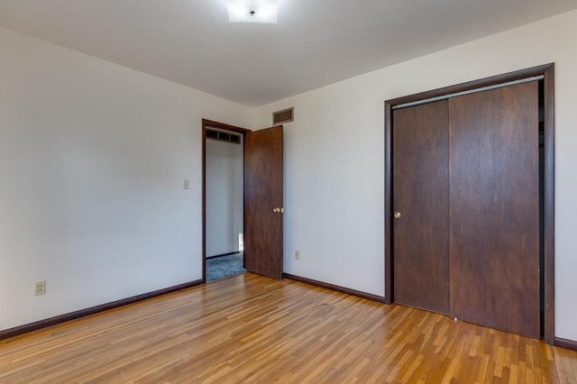 unfurnished bedroom featuring light wood-style floors, visible vents, a closet, and baseboards