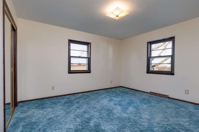 unfurnished bedroom featuring visible vents, multiple windows, baseboards, and carpet floors