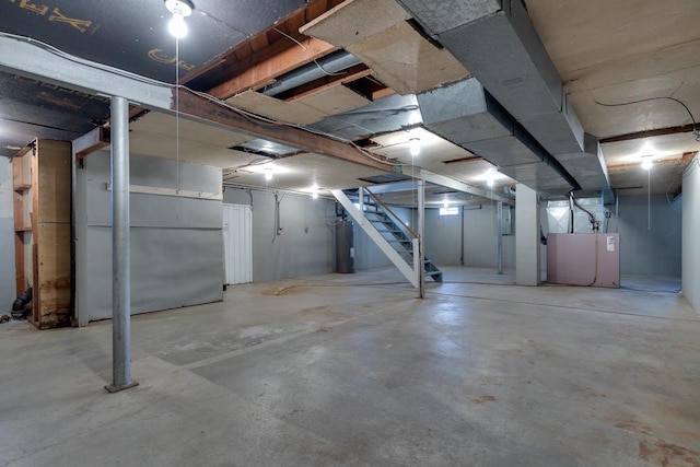 unfinished basement featuring stairs and heating unit