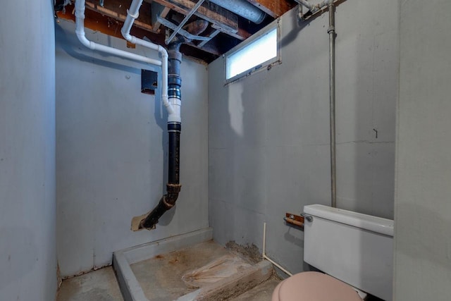 bathroom featuring unfinished concrete floors and toilet