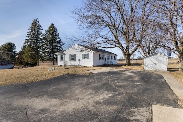 view of front of home featuring a storage unit, an outbuilding, and driveway