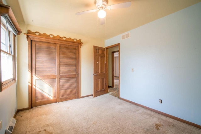 unfurnished bedroom with visible vents, light carpet, baseboards, and a ceiling fan