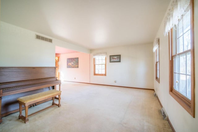 empty room featuring visible vents, light colored carpet, and baseboards