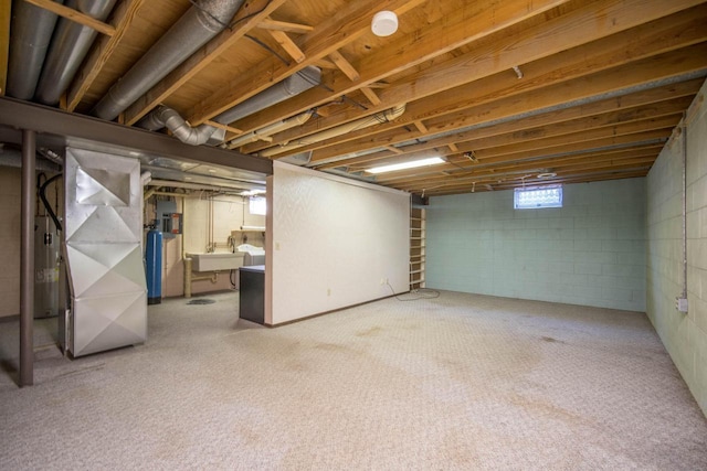 basement featuring heating unit, water heater, and a sink