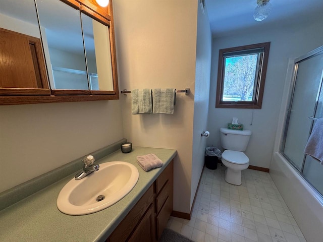 bathroom with toilet, vanity, baseboards, and shower / bath combination with glass door