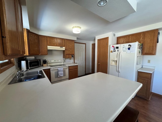 kitchen with white appliances, a sink, light countertops, under cabinet range hood, and brown cabinets