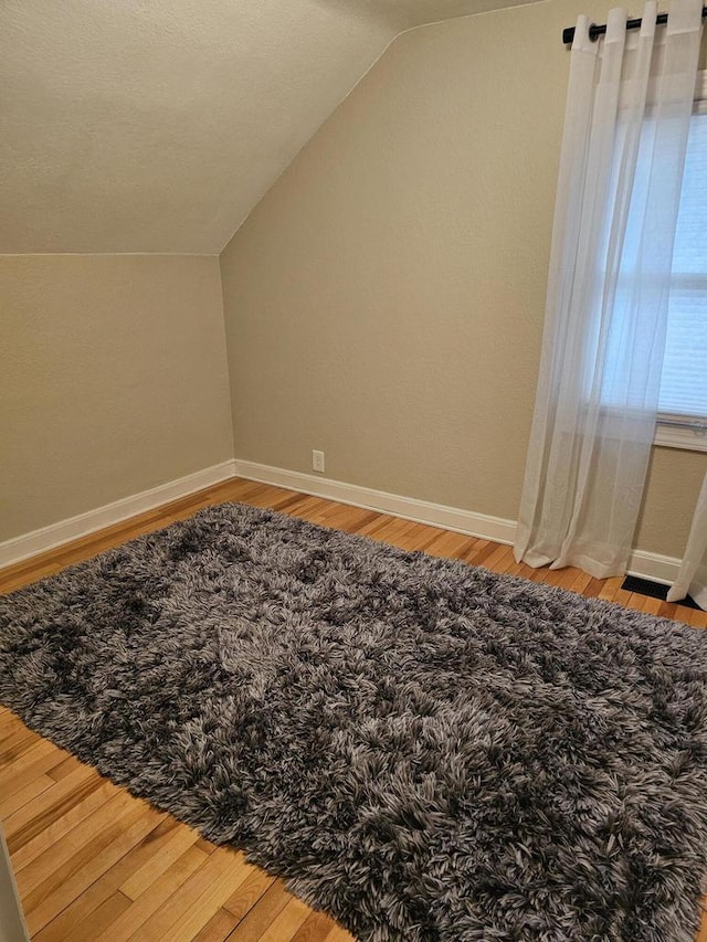 bonus room featuring baseboards, light wood-style floors, and vaulted ceiling