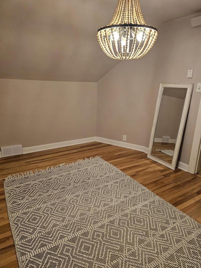 bonus room with visible vents, baseboards, vaulted ceiling, wood finished floors, and a notable chandelier