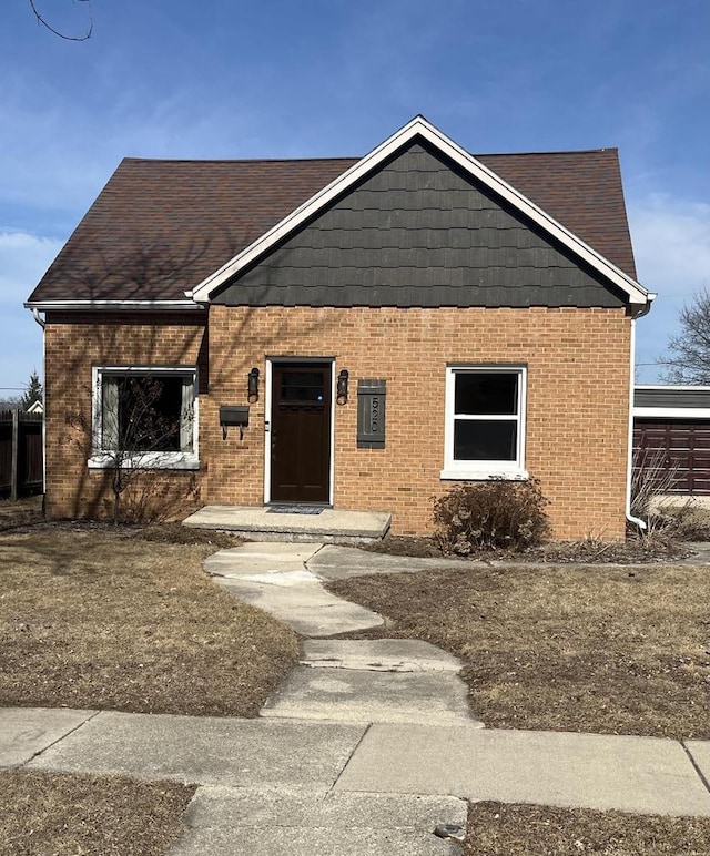 view of front facade with brick siding and roof with shingles