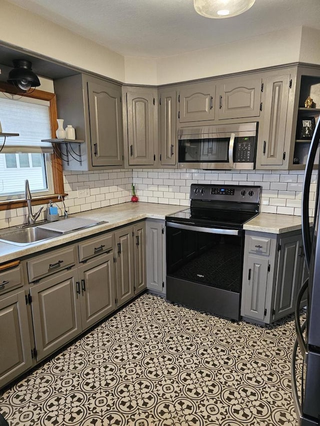 kitchen featuring stainless steel microwave, range with electric cooktop, gray cabinetry, open shelves, and a sink