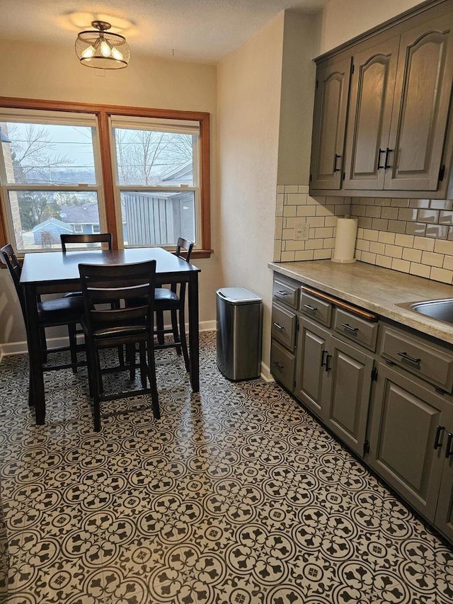 kitchen featuring decorative backsplash, light countertops, baseboards, and a sink