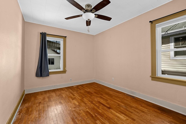 spare room with visible vents, a ceiling fan, baseboards, and hardwood / wood-style flooring