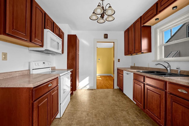 kitchen with baseboards, light countertops, a notable chandelier, white appliances, and a sink