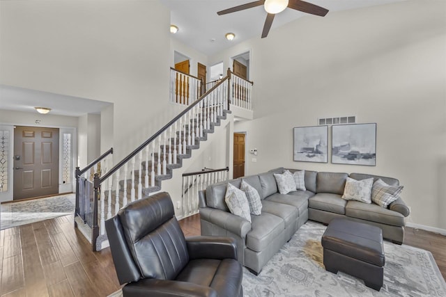 living area with visible vents, baseboards, ceiling fan, stairway, and wood finished floors