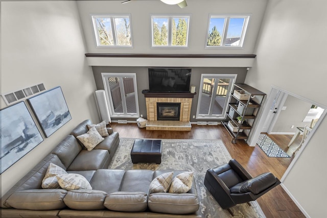 living area featuring visible vents, a high ceiling, wood finished floors, and a fireplace