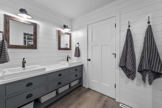 bathroom featuring double vanity, wood finished floors, and a sink