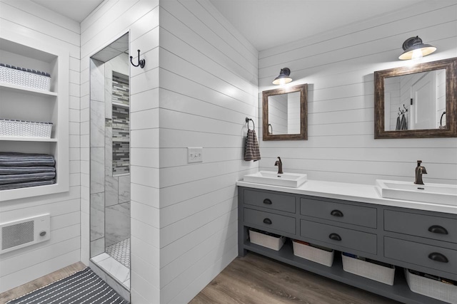 full bathroom with double vanity, walk in shower, wood finished floors, and a sink