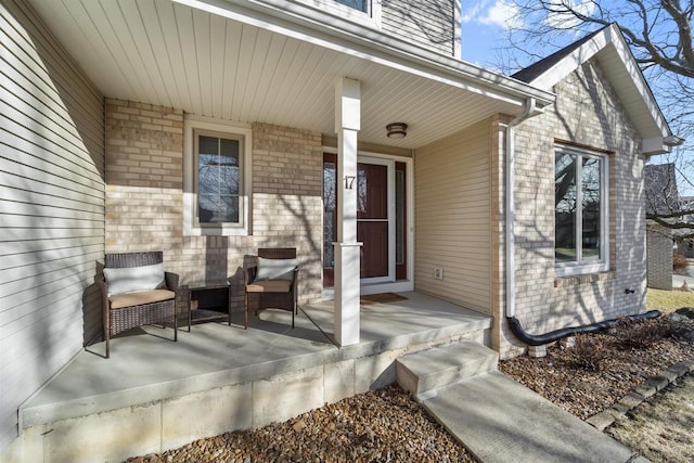 view of exterior entry with brick siding and covered porch