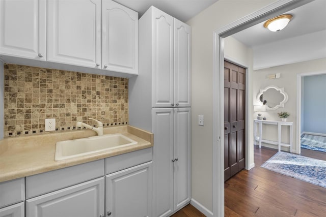 kitchen featuring a sink, white cabinets, light countertops, decorative backsplash, and dark wood-style flooring