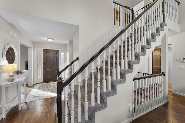 entrance foyer featuring baseboards, a towering ceiling, stairs, and hardwood / wood-style flooring