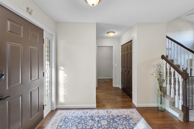 entryway with stairway, wood finished floors, and baseboards