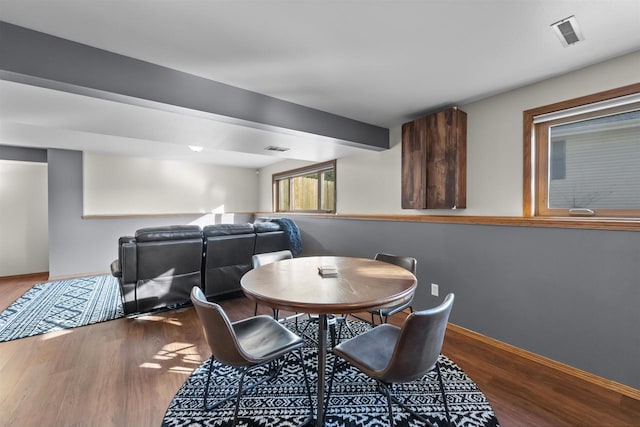 dining room with beam ceiling, wood finished floors, visible vents, and baseboards