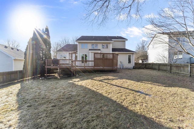 rear view of property with a deck, a lawn, and a fenced backyard