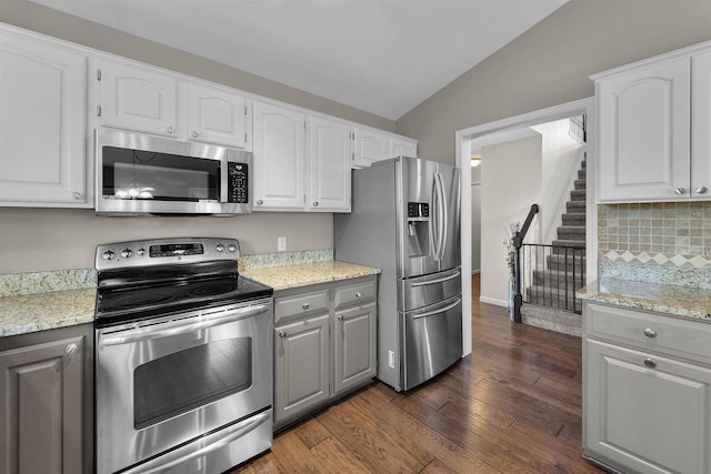 kitchen with light stone counters, stainless steel appliances, lofted ceiling, and dark wood-style flooring