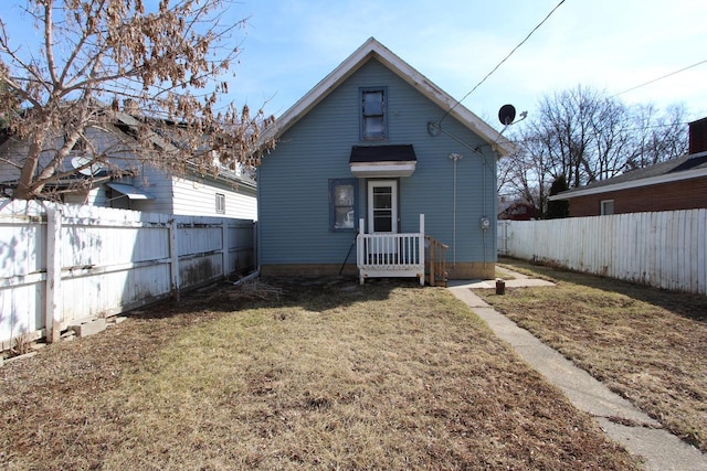 rear view of house with a lawn and a fenced backyard