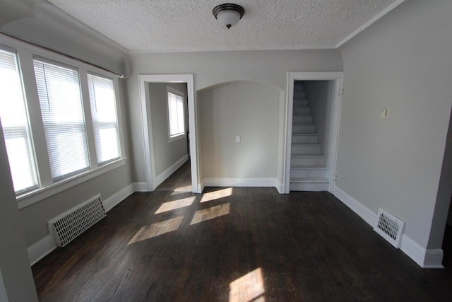 unfurnished room featuring visible vents, baseboards, a textured ceiling, and wood finished floors