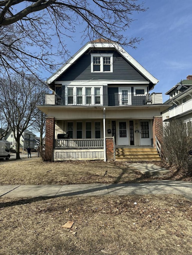 view of front facade with brick siding, covered porch, and a balcony