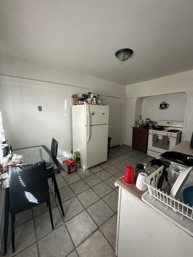 kitchen featuring white appliances and light tile patterned flooring