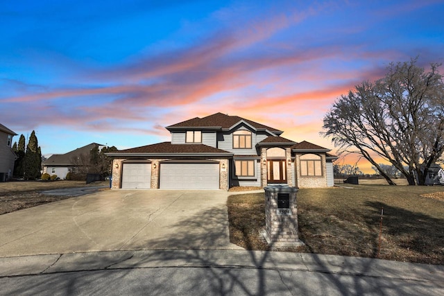 view of front facade featuring a yard, brick siding, a garage, and driveway