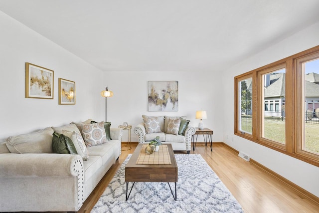 living room featuring light wood-style flooring, baseboards, and visible vents