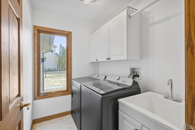 washroom featuring a sink, baseboards, cabinet space, and washing machine and dryer